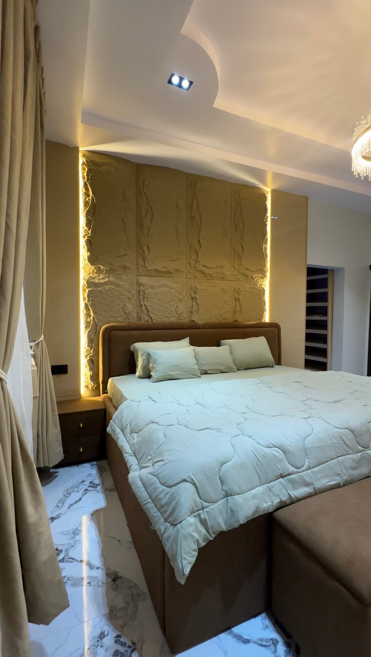 Warm bedroom interior with layered lighting and textured wall detailing by Jess Interiors